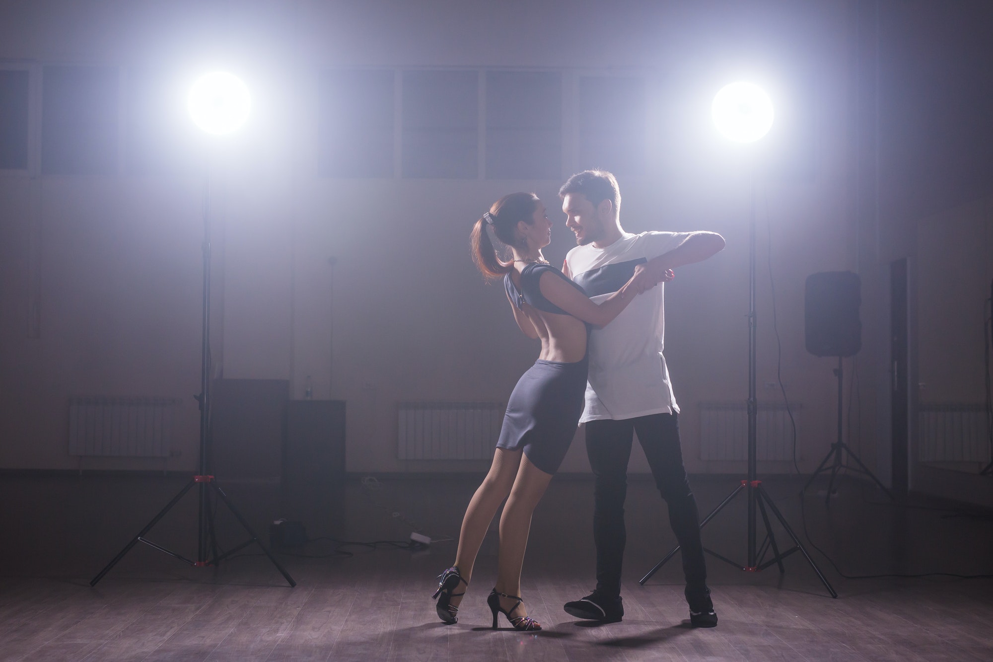 Young couple dancing social danse kizomba or bachata or semba or taraxia in dancing class background